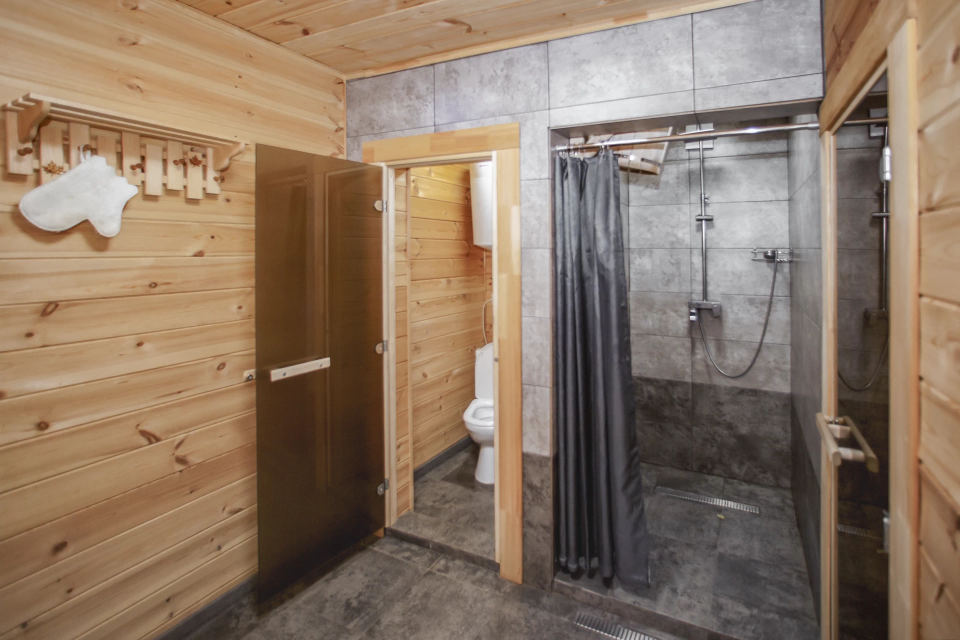 Гигиеническая зона расположена за дверьми парной. Она оборудована умывальником, душевой с обливным ведром, туалетом и системой слива.