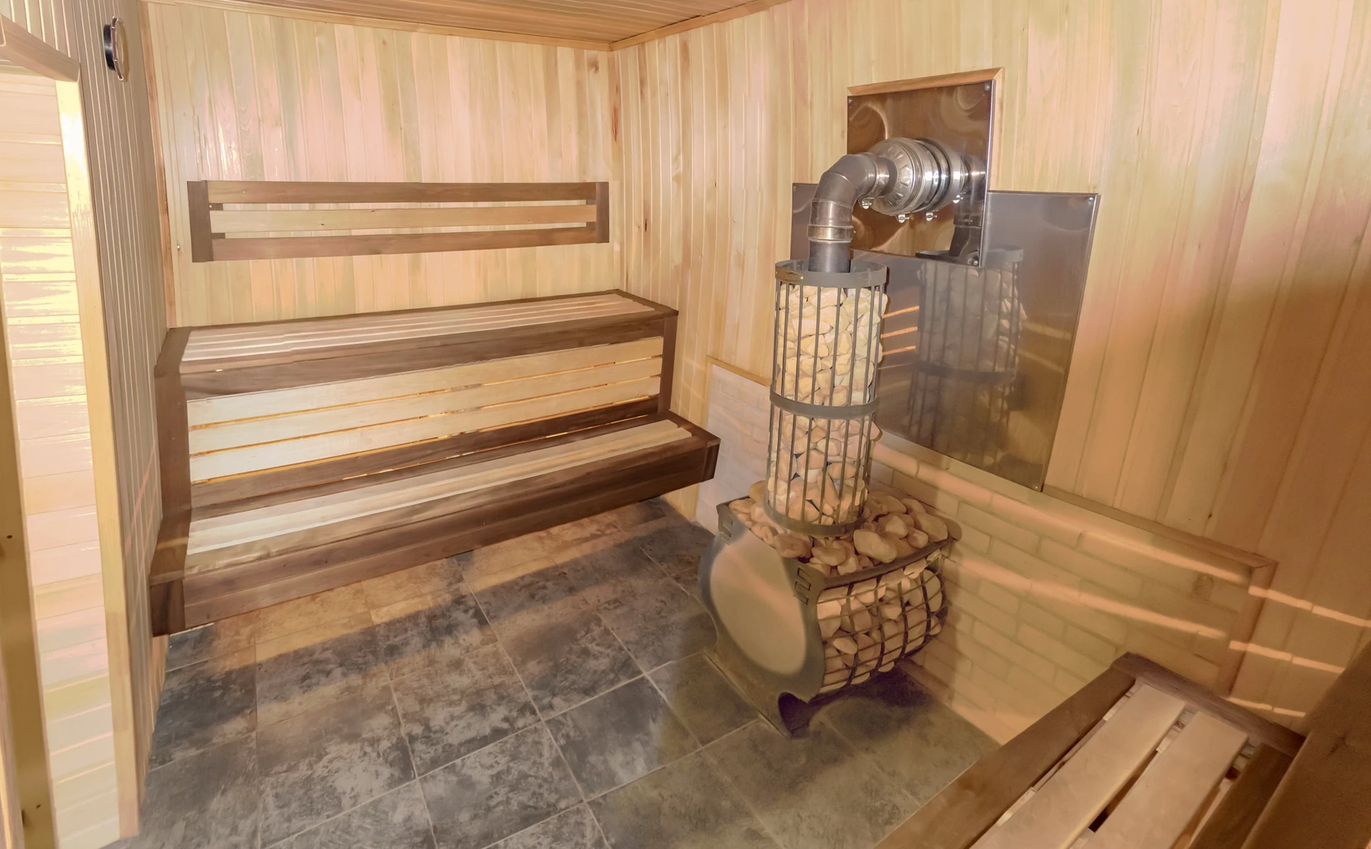 Дровяная печь с каменной кладкой смягчает жар и позволяет насыщать пар влагой и целебными ароматами эфирных масел.